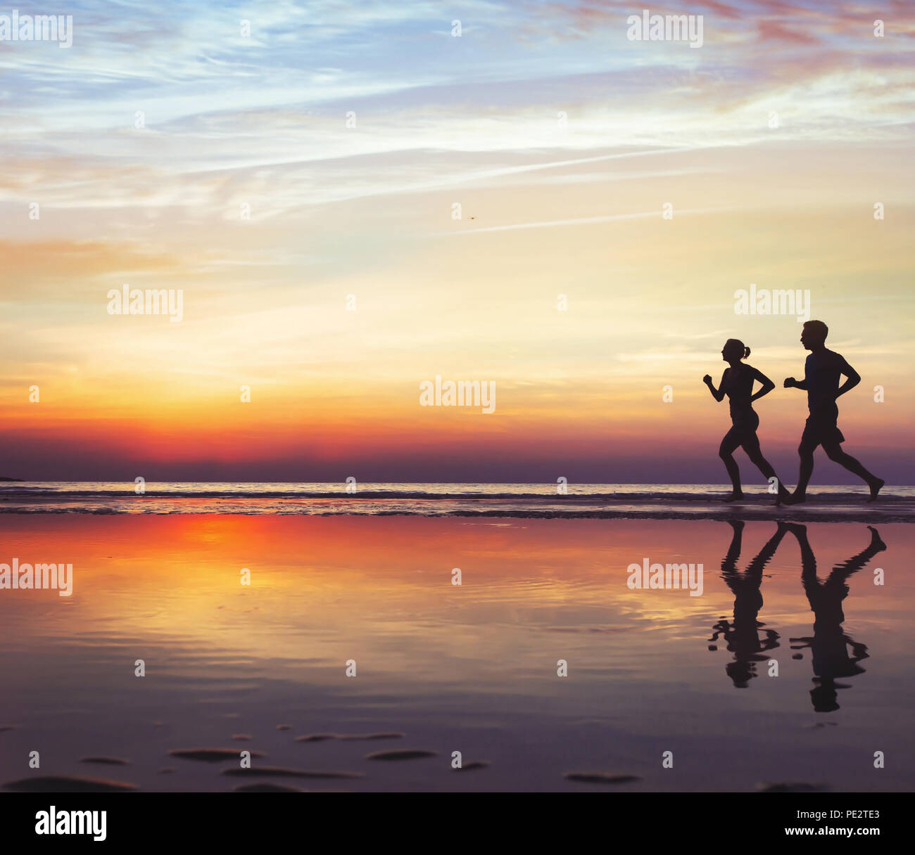 Deporte y salud, dos corredores en la playa, la silueta de la gente haciendo footing al atardecer, el hombre y la mujer un estilo de vida saludable Foto de stock