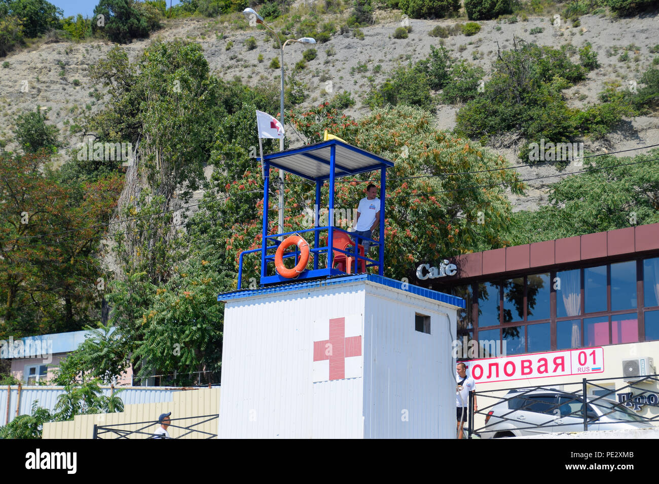 Novorossisk, Rusia - Agosto 06, 2018: el socorrista en la torre de rescate observa la orilla. Playa de Novorossiysk. Foto de stock