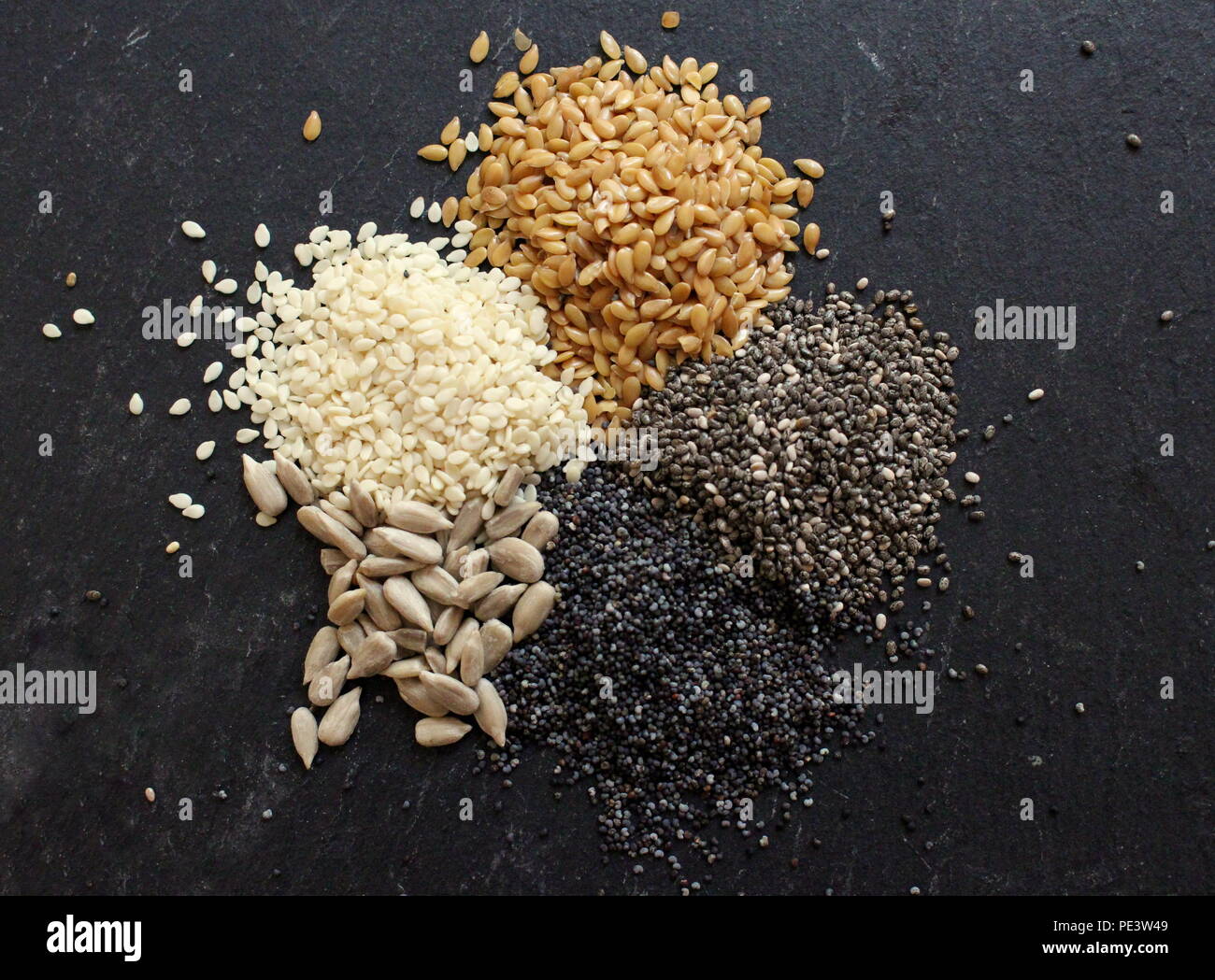 Cerrar arriba abajo fotografía de una variedad de semillas, incluidas las semillas de amapola azul, sésamo, girasol y las semillas de chia Foto de stock
