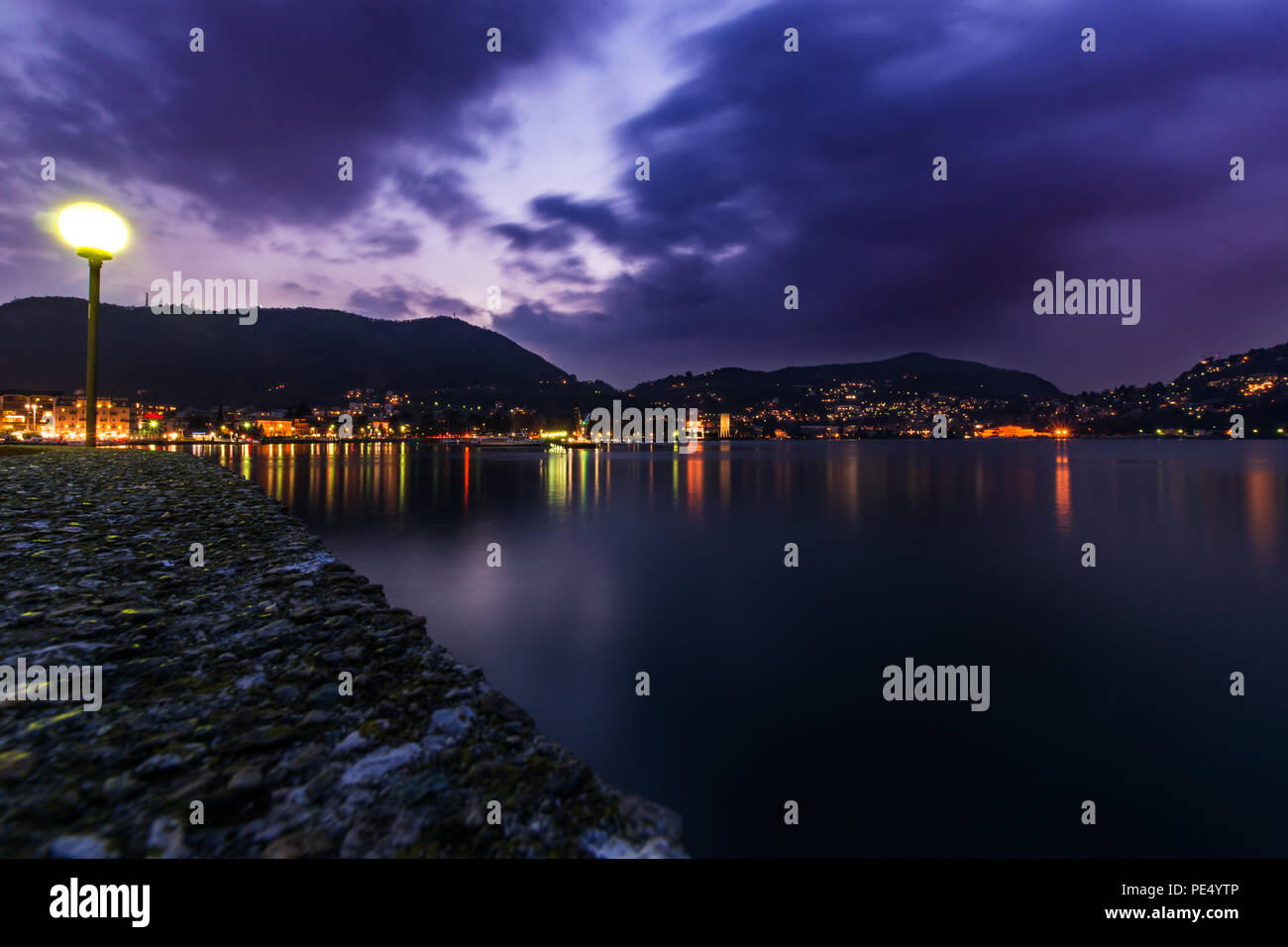 La larga exposición del lago de Como, Lombardía, Italia, Bello efecto de luces sobre el agua. Cielo púrpura. Foto de stock