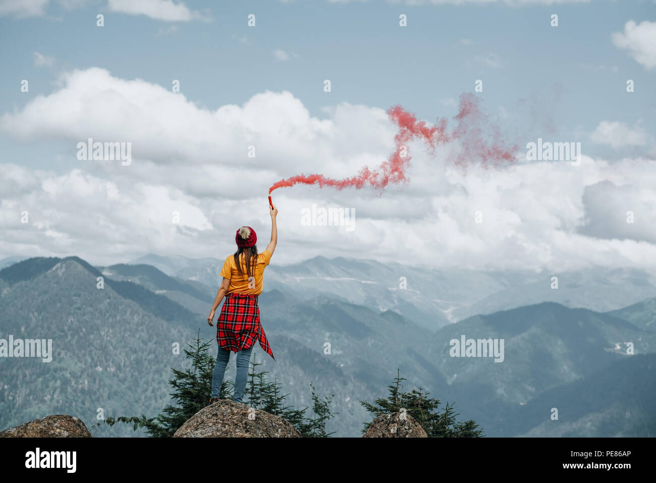 Mujer en el pico de la montaña con destellos rojos.Inspiración concepto Foto de stock