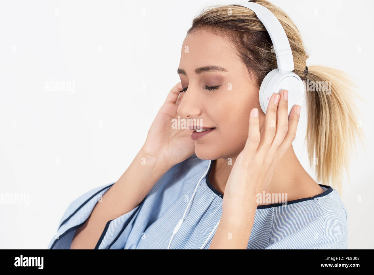 Pretty girl escuchando música con sus auriculares sobre fondo blanco. Foto de stock