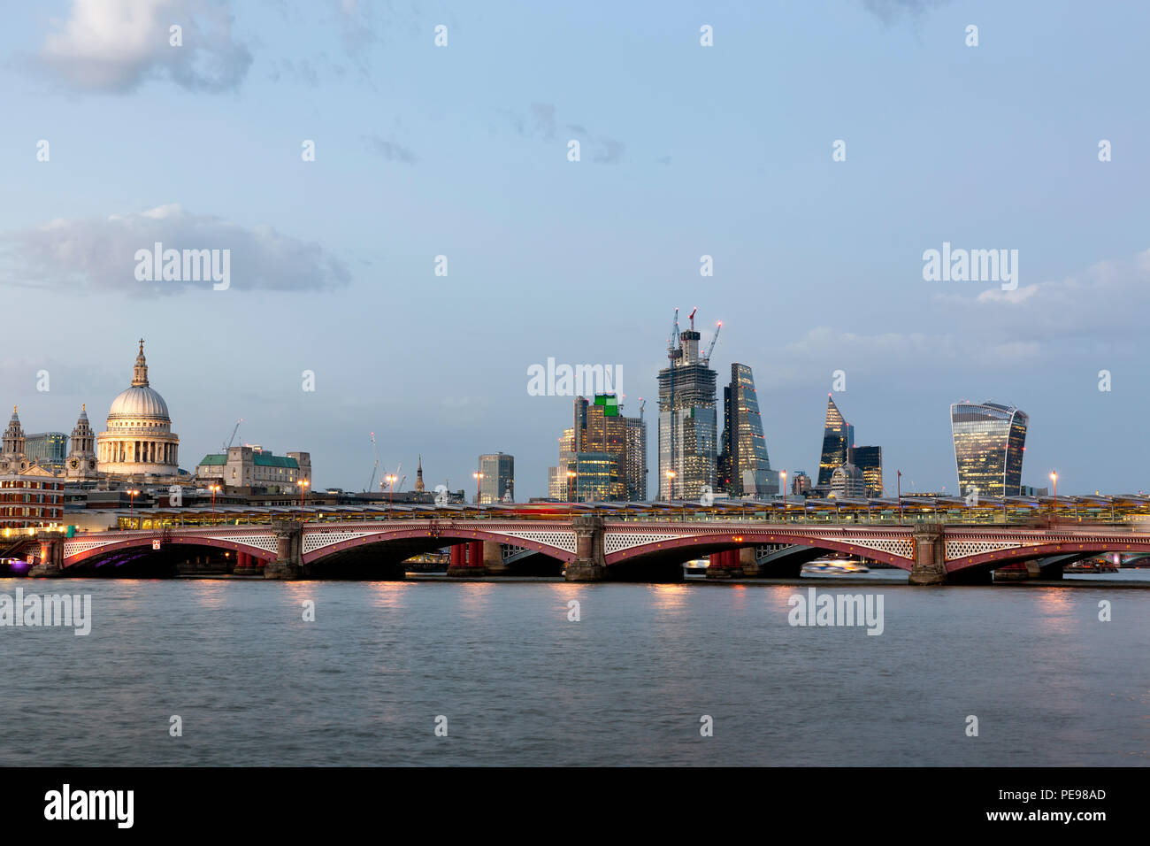 Blackfriars Bridge y la ciudad de Londres, visto desde la orilla sur del río Támesis en penumbra Foto de stock