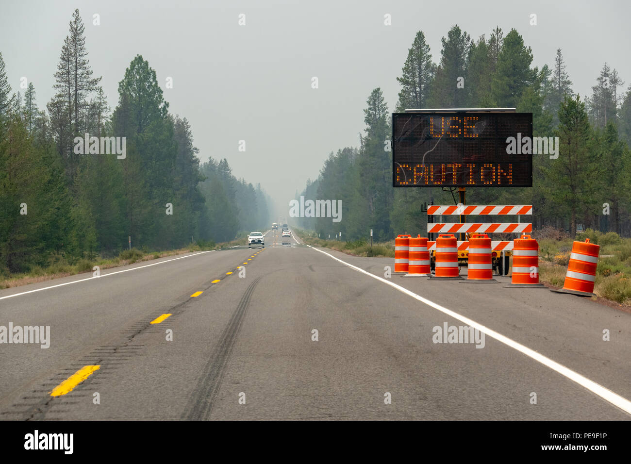 La autopista llena de humo de incendios en el sur de Oregon, firmar al lado de la carretera de 'Precaución'. Foto de stock