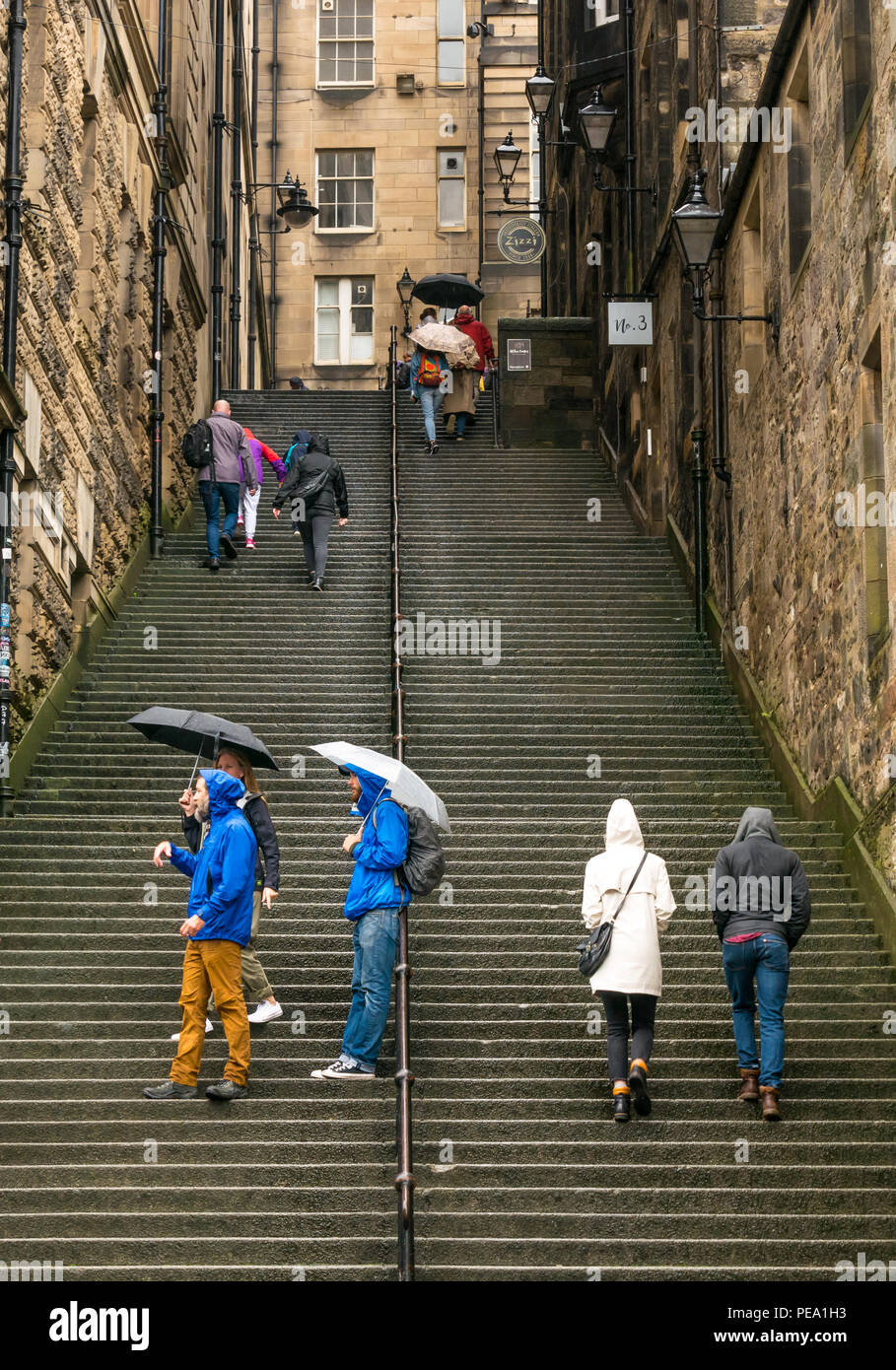 Los turistas con paraguas en la lluvia subir escalones largos en alley, Warriston Cockburn Street, cerca de Royal Mile, Edimburgo, Escocia, Reino Unido Foto de stock