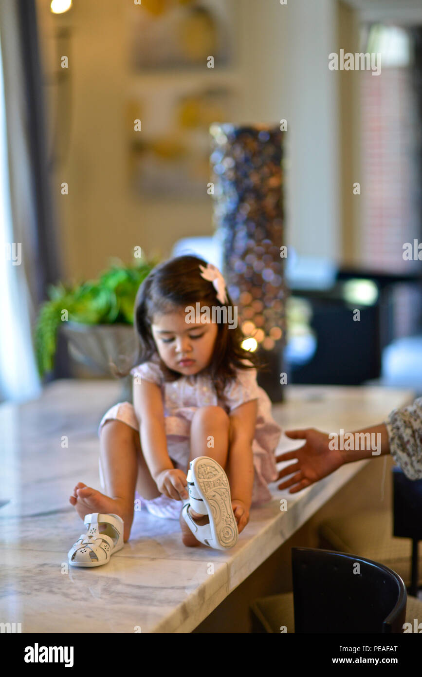 Dos años de edad, niña aprende cómo poner sus zapatos Foto de stock