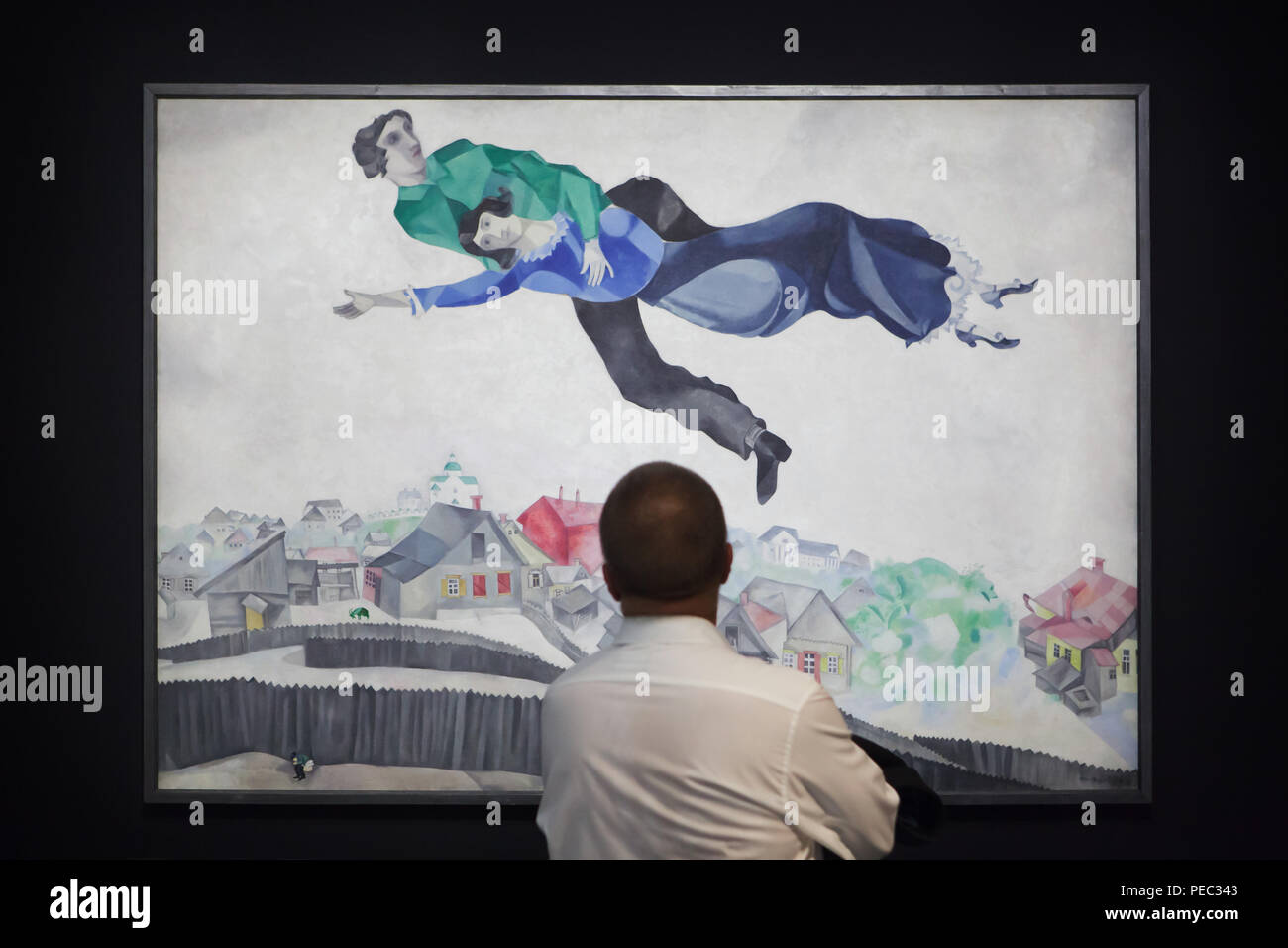 Visitante delante de la pintura 'Over the Town' por el pintor modernista ruso Marc Chagall (1914-1918) que se muestra en la exposición del Centro Georges Pompidou de París, Francia. La exposición dedicada a la vanguardia rusa en Vitebsk (1918-1922) se extiende hasta el 16 de julio de 2018. Foto de stock