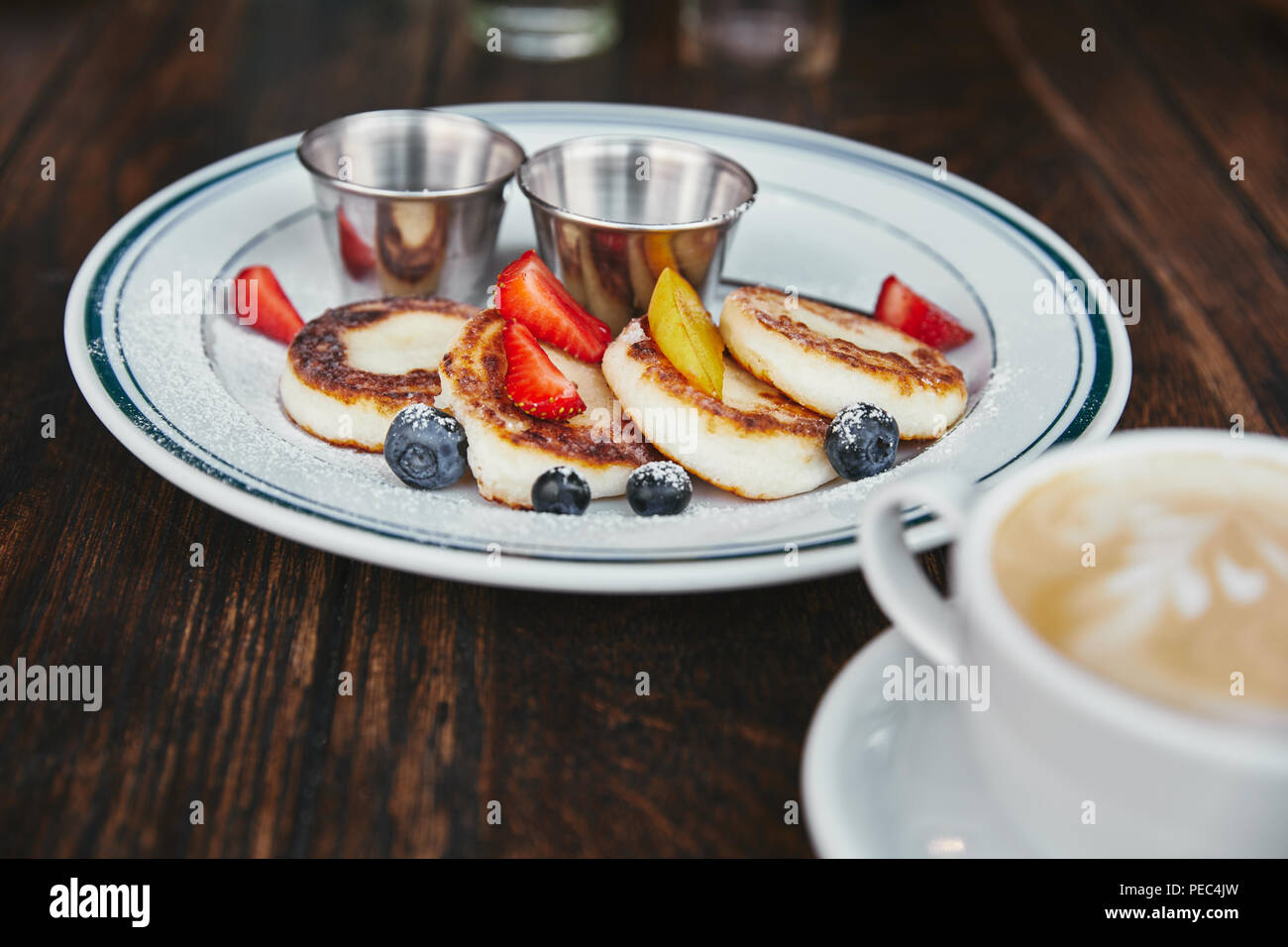 Delicious syrniki sobre el plato y la taza de café sobre la mesa de madera rústica Foto de stock