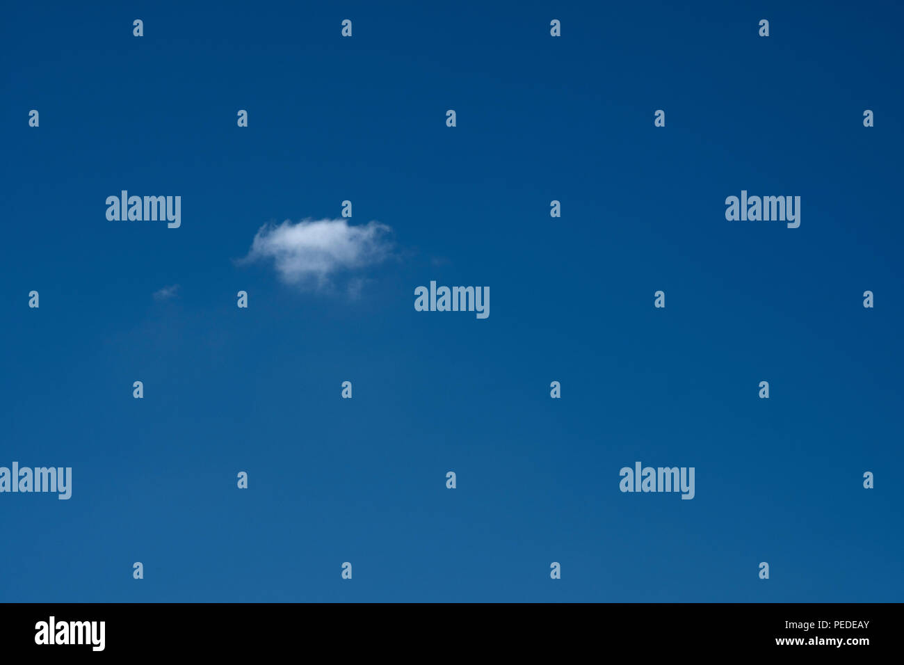 Nube pequeña en una gran extensión del despejado cielo azul profundo. Foto de stock