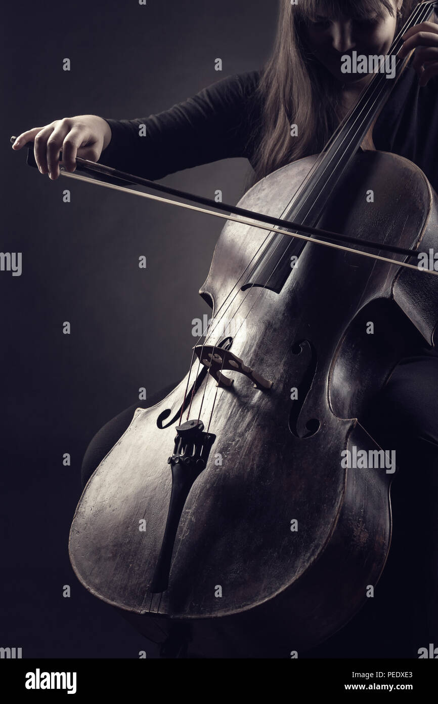 Close-up de la violonchelista tocando música clásica en el cello contra un fondo negro Foto de stock
