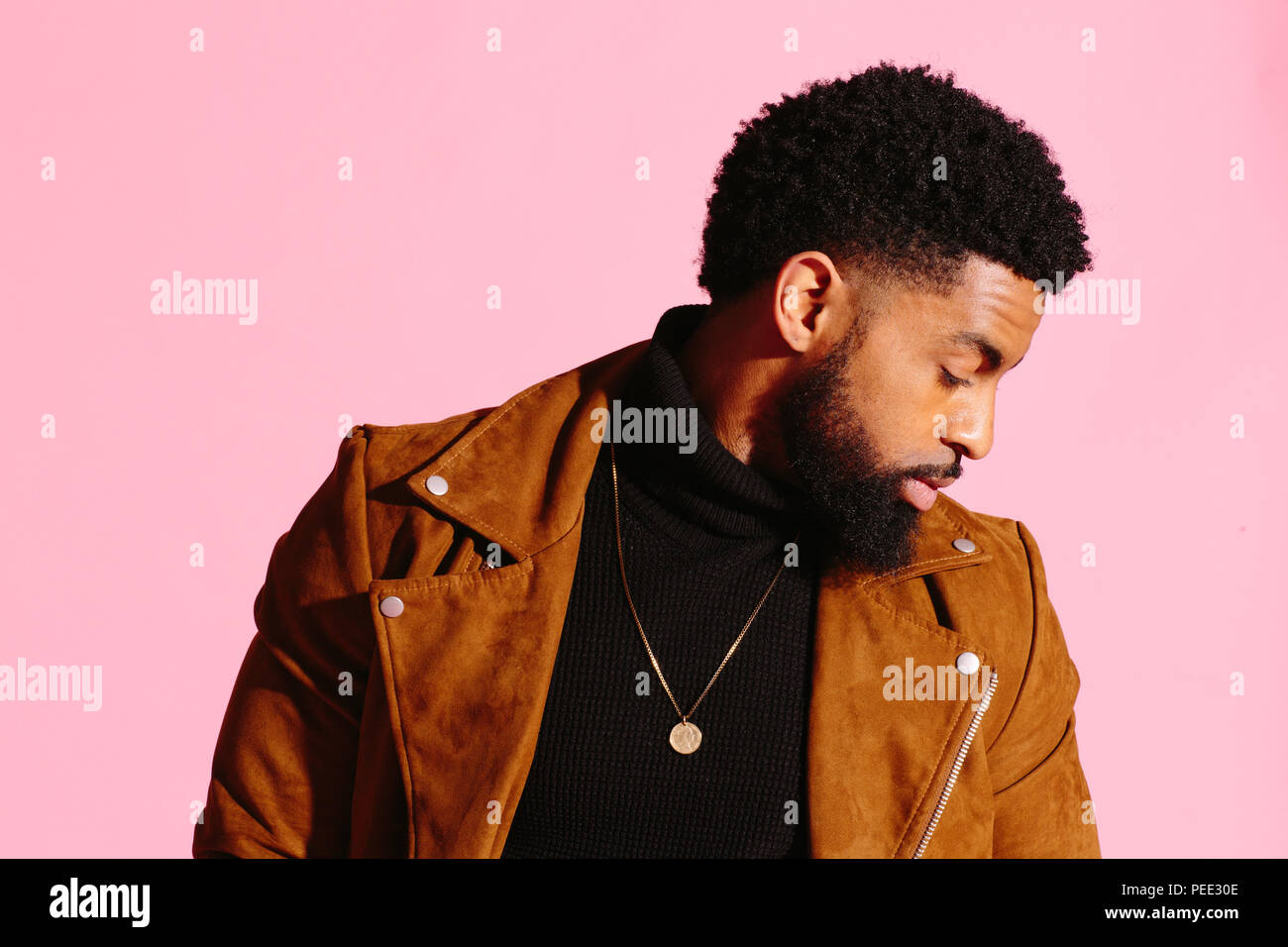 Elegante, guapo y cool hombre afroamericano con barba, aislado sobre fondo rosa studio Foto de stock