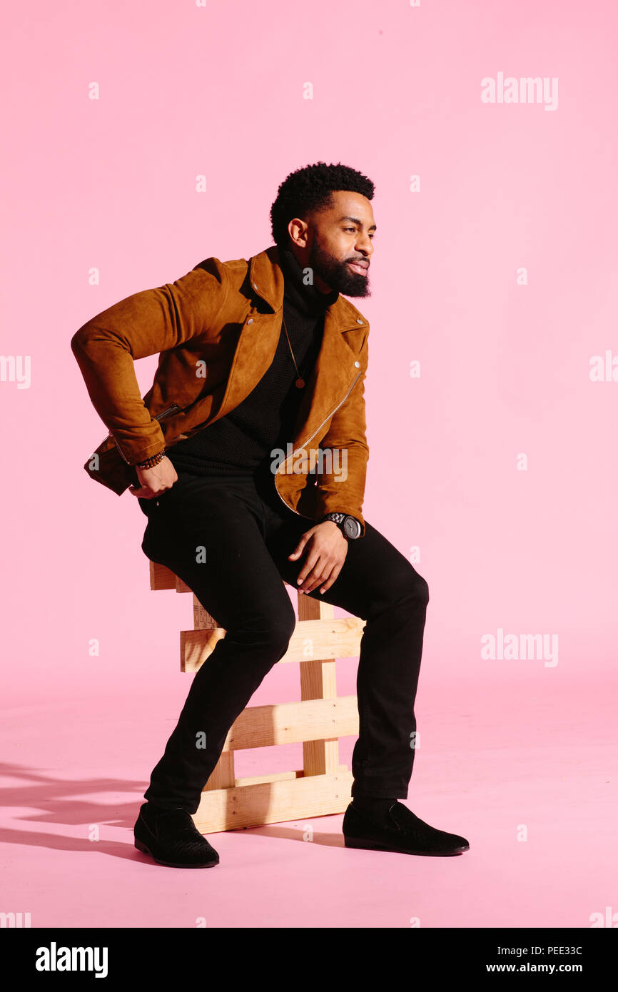 Elegante, guapo y cool hombre afroamericano con barba, aislado sobre fondo rosa studio Foto de stock