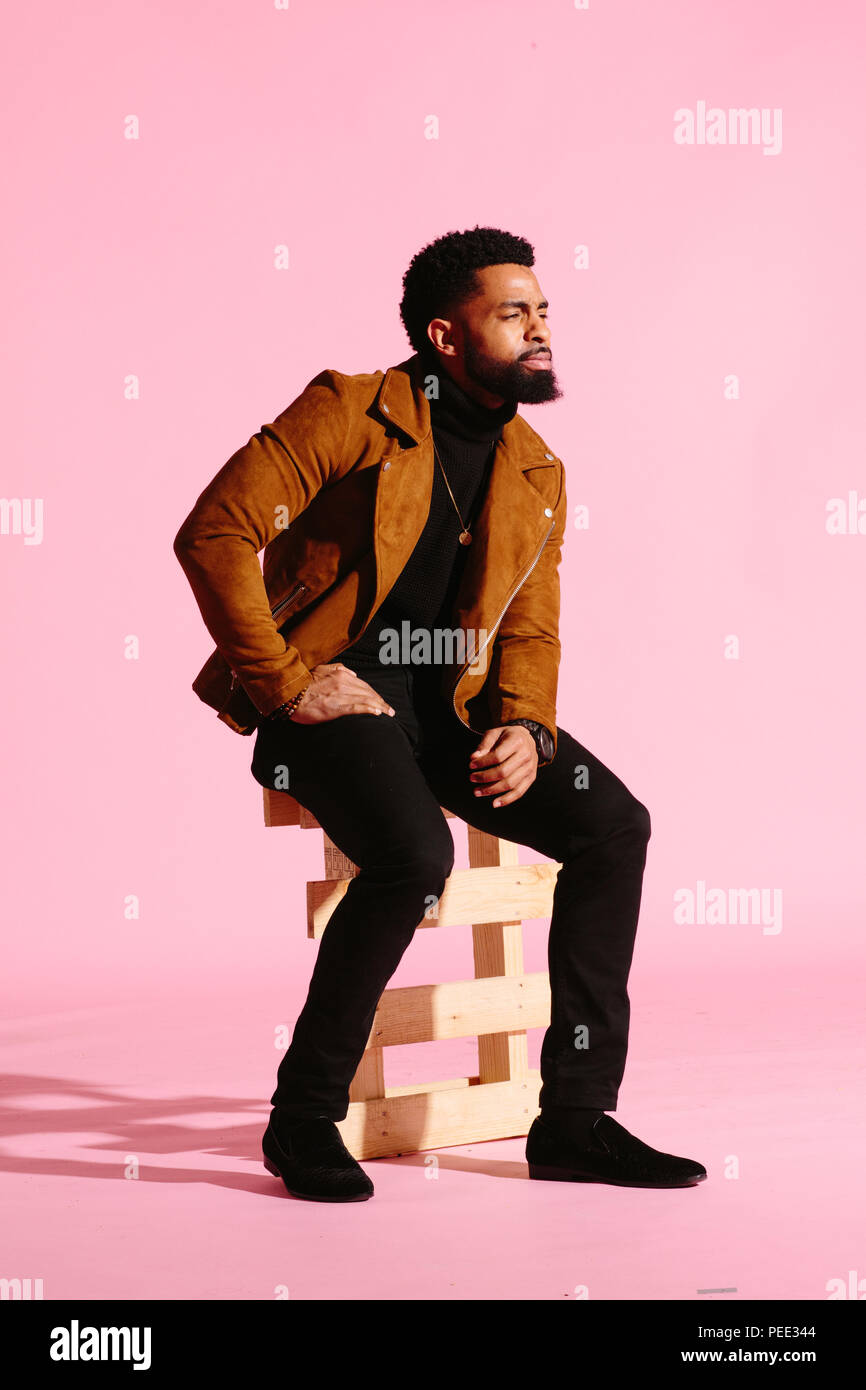 Elegante, guapo y cool hombre afroamericano con barba, aislado sobre fondo rosa studio Foto de stock