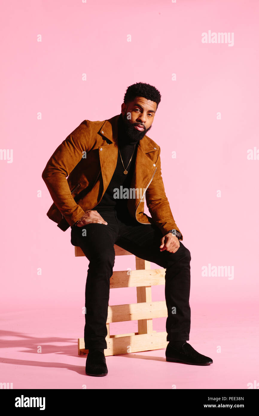 Elegante, guapo y cool hombre afroamericano con barba, aislado sobre fondo rosa studio Foto de stock