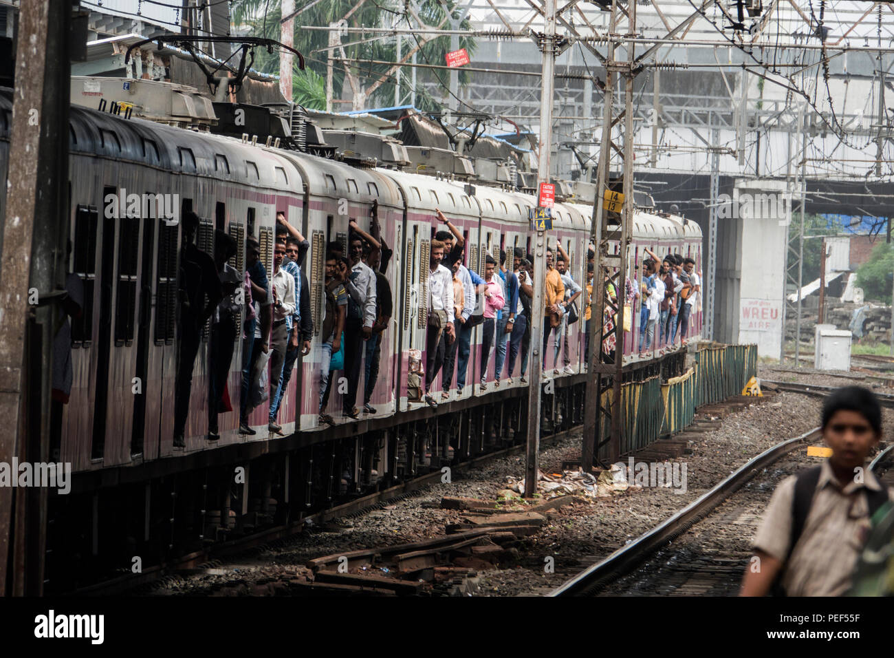 Los trenes de pasajeros colgando de la puerta sobre un ferrocarril suburbano de Bombay en tren la estación de Bandra, Mumbai, India Foto de stock