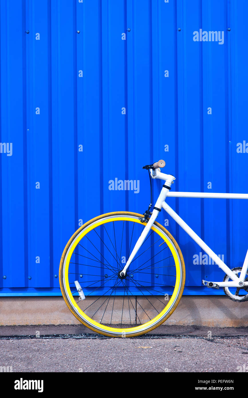 Letonia, Riga. Julio de 2015. Bicicleta blanca con ruedas de color amarillo  en las paredes de color azul con rayas en un brillante día soleado  Fotografía de stock - Alamy