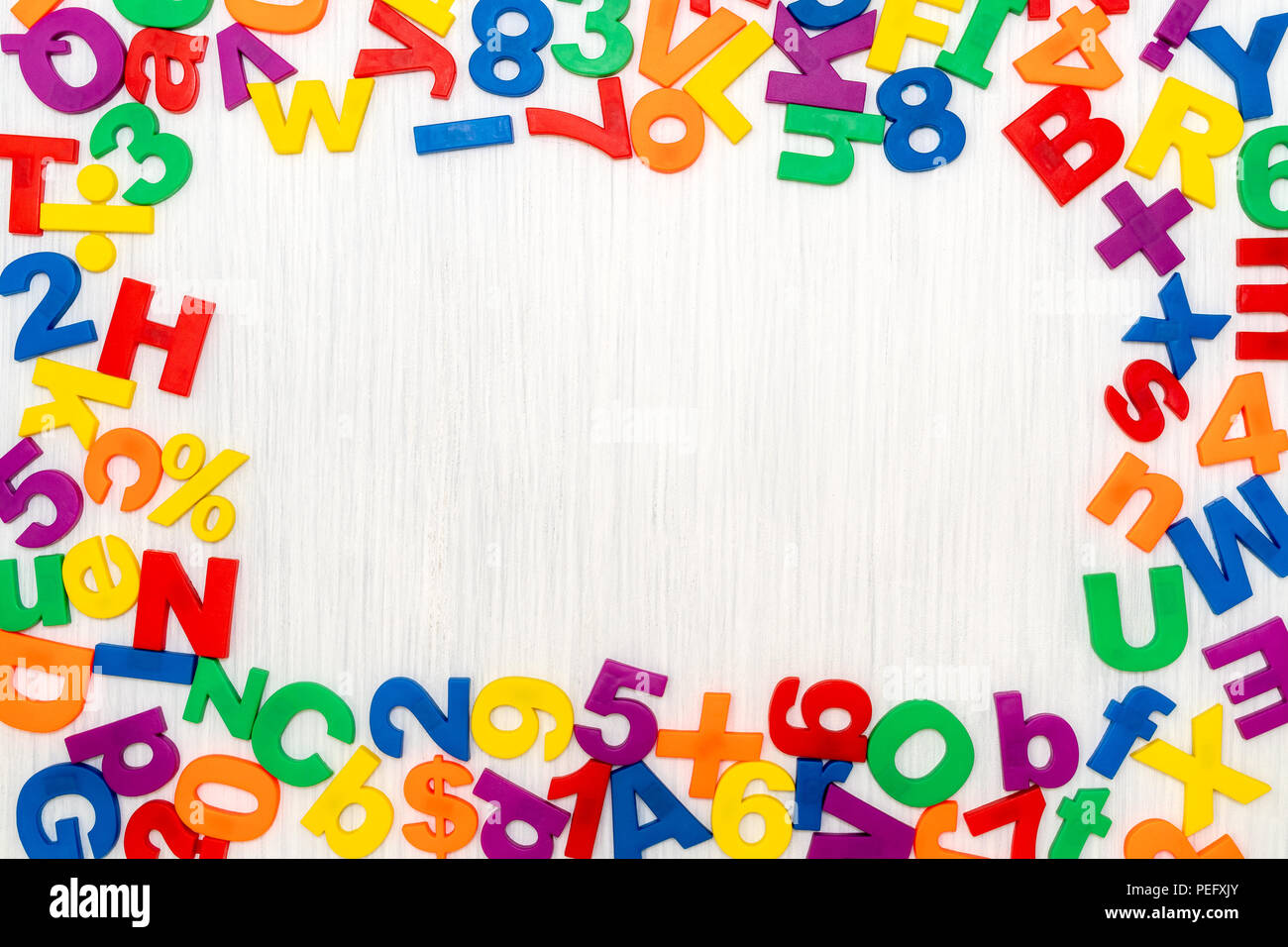 Números y letras de plástico colorido como marco en un fondo de madera