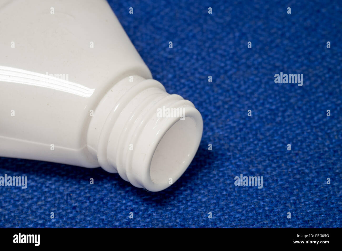 Boca rosca de botella de plástico PET de color blanco sobre la superficie de tela azul para alimentos y medicamentos. Foto de stock