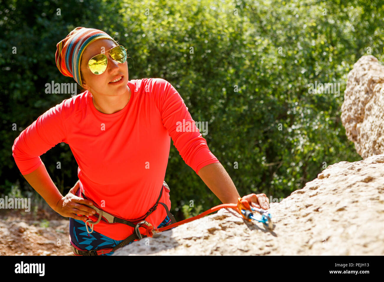 Foto de mujer sonriente escalador con gafas de sol sentado Foto de mujer sonriente escalador con gafas de sol sentado