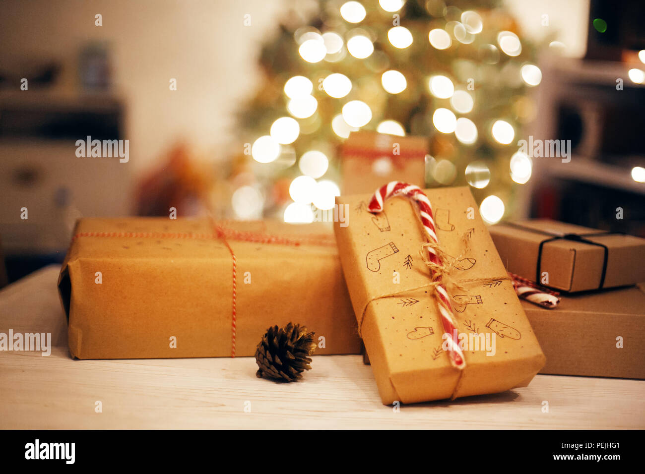 Regalos de Navidad con estilo en luces de mesa de madera en el fondo del  árbol de navidad en la iluminación navideña en la víspera. Espacio para el  texto. moderna embarcación don