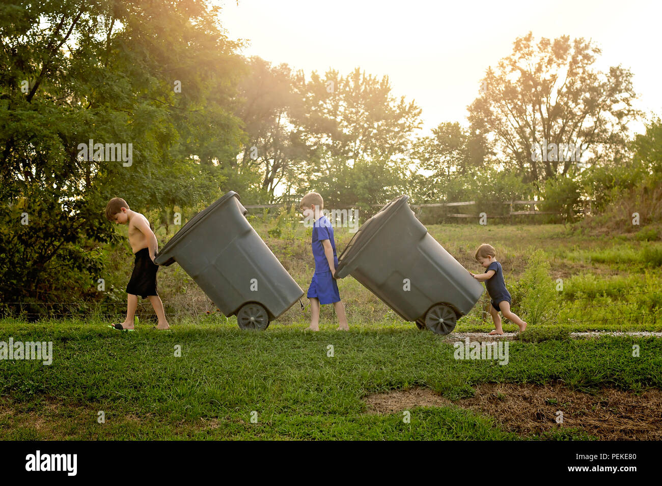 Tres jóvenes sacando los cubos de basura Foto de stock