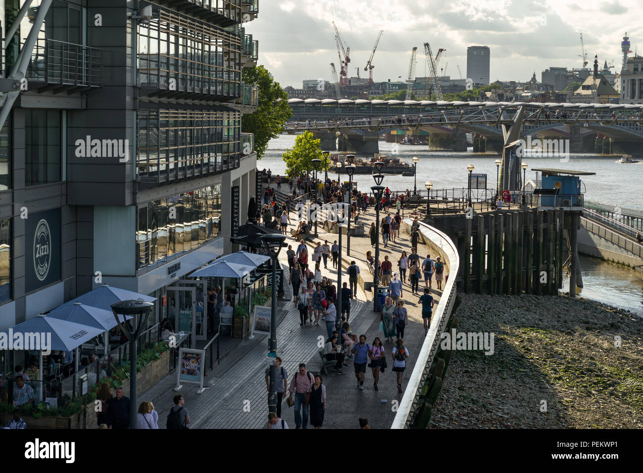 Edificio de Riverside con Zizzi restaurante, gente caminando a lo largo de Bankside con el río Támesis y en el fondo del Puente del Milenio, Londres, Reino Unido. Foto de stock