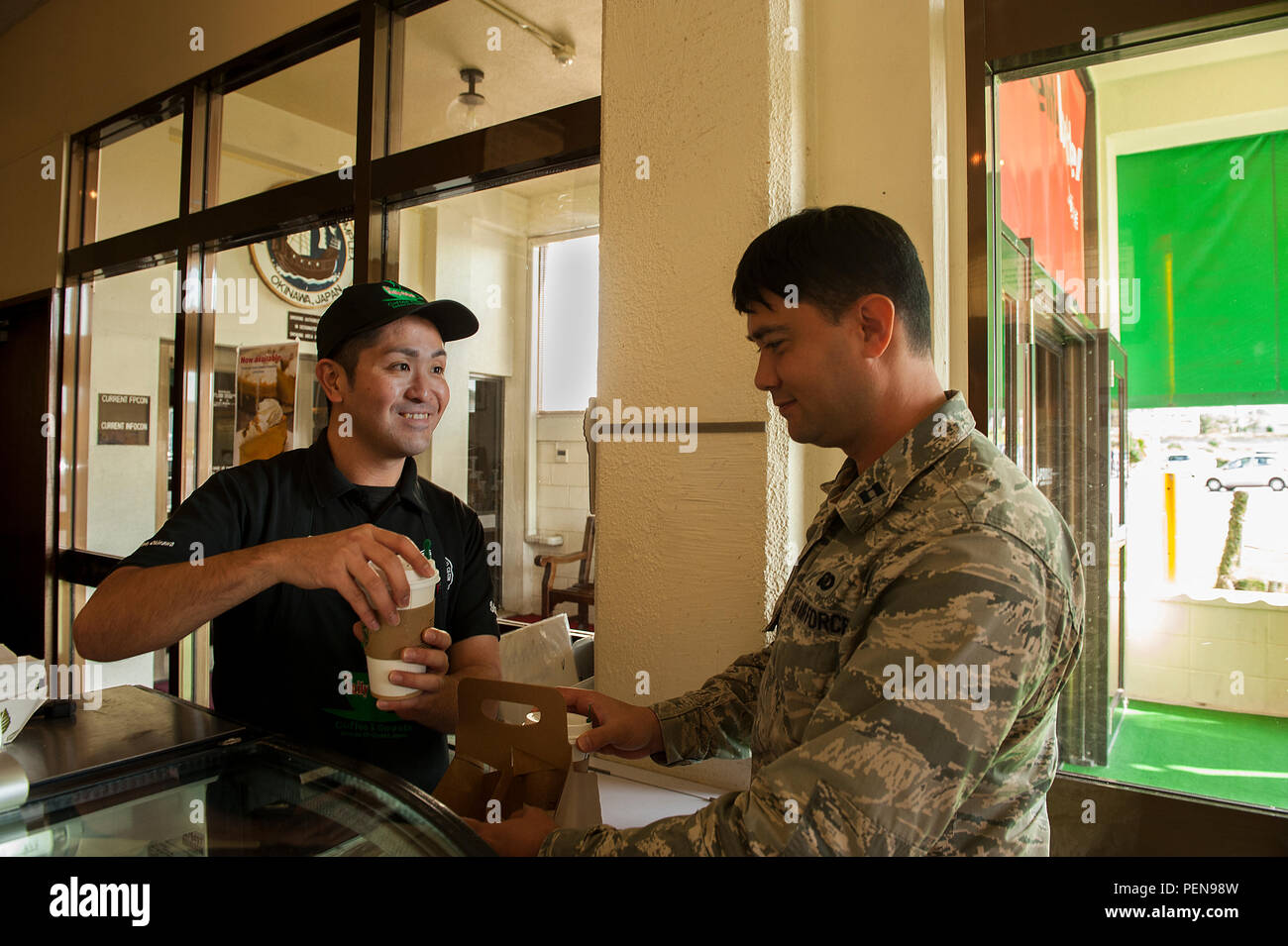 El capitán de la Fuerza Aérea de EE.UU. Joshua Caragan, 18ª Ala oficial de igualdad de oportunidades, obtiene el café de Koji, Kamekawa Diaria Cafetería cajero, en el balancín NCO Club, del 30 de diciembre de 2015, en la Base Aérea de Kadena, Japón. El basculante NCO Club está cerrando sus puertas para dar paso a una nueva planta viniendo en 2017. (Ee.Uu. Foto de la fuerza aérea por Aerotécnico de Primera Clase Corey M. Pettis) Foto de stock