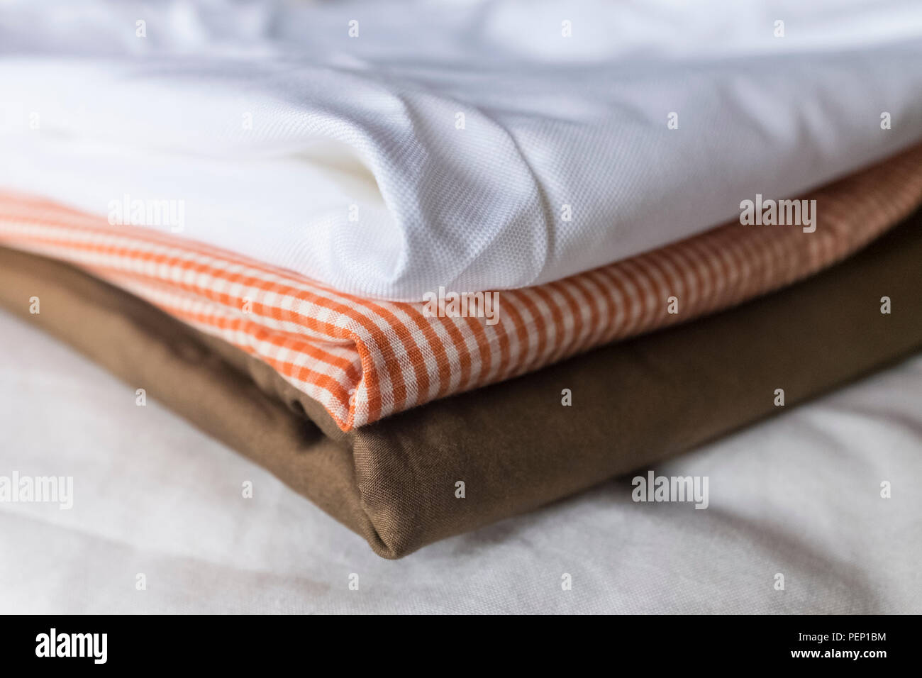 Plegar una pila de tres distintas telas, blanco, naranja verificar y telas  de color bronce Fotografía de stock - Alamy