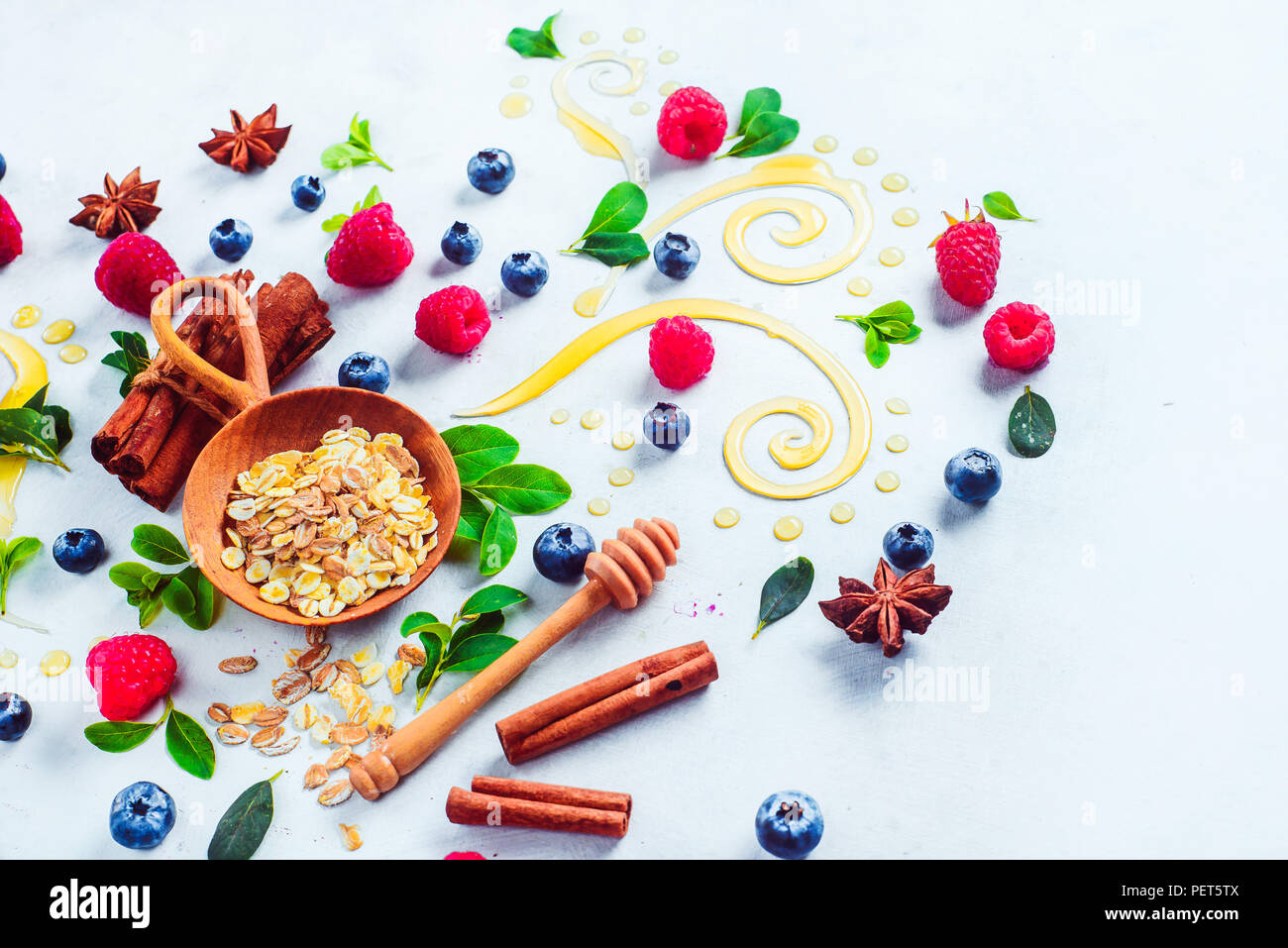 Concepto de desayuno saludable con avena, miel, canela y bayas sobre un fondo de madera blanca. Cocinar gachas plana con copia espacio laical Foto de stock