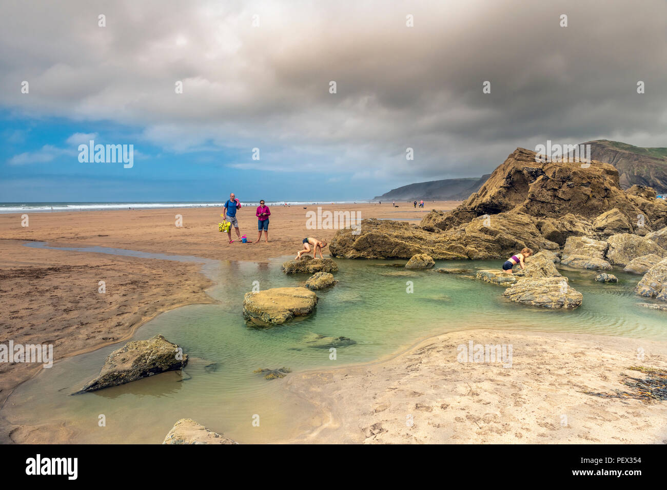 El clima del REINO UNIDO - La hermosa playa a Sandymouth demuestra ser populares entre los turistas, mientras el sol se pone finalmente en una apariencia como la baja y neblina c Foto de stock