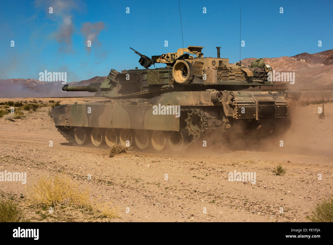 Un M1A1 Abrams Del tanque principal de batalla con la empresa A, 1er  Batallón de Tanques, avanza a lo largo de una carretera mientras recibe  apoyo de fuego indirecto de artillería durante