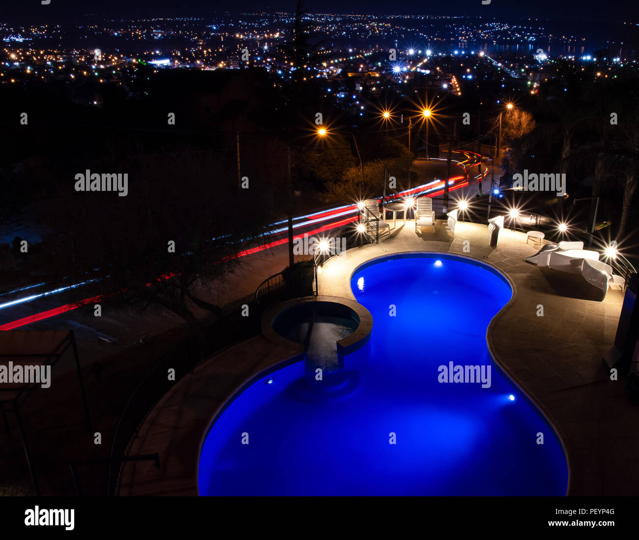 La piscina por la noche con las luces de la ciudad en el fondo y alquiler de senderos en la calle Foto de stock