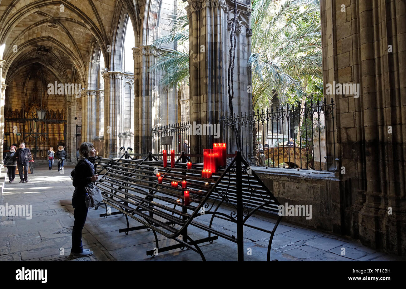 Una mujer se encuentra en un rack de velas en el Claustro de la Catedral de Barcelona Zona ajardinada de España Foto de stock