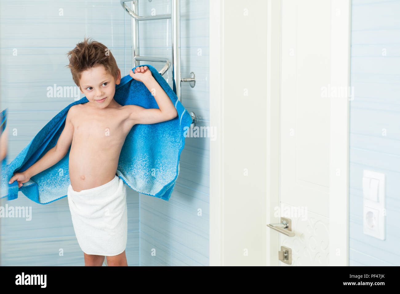 Feliz poco saludable kid secar su cuerpo con una toalla de baño interior  azul Fotografía de stock - Alamy