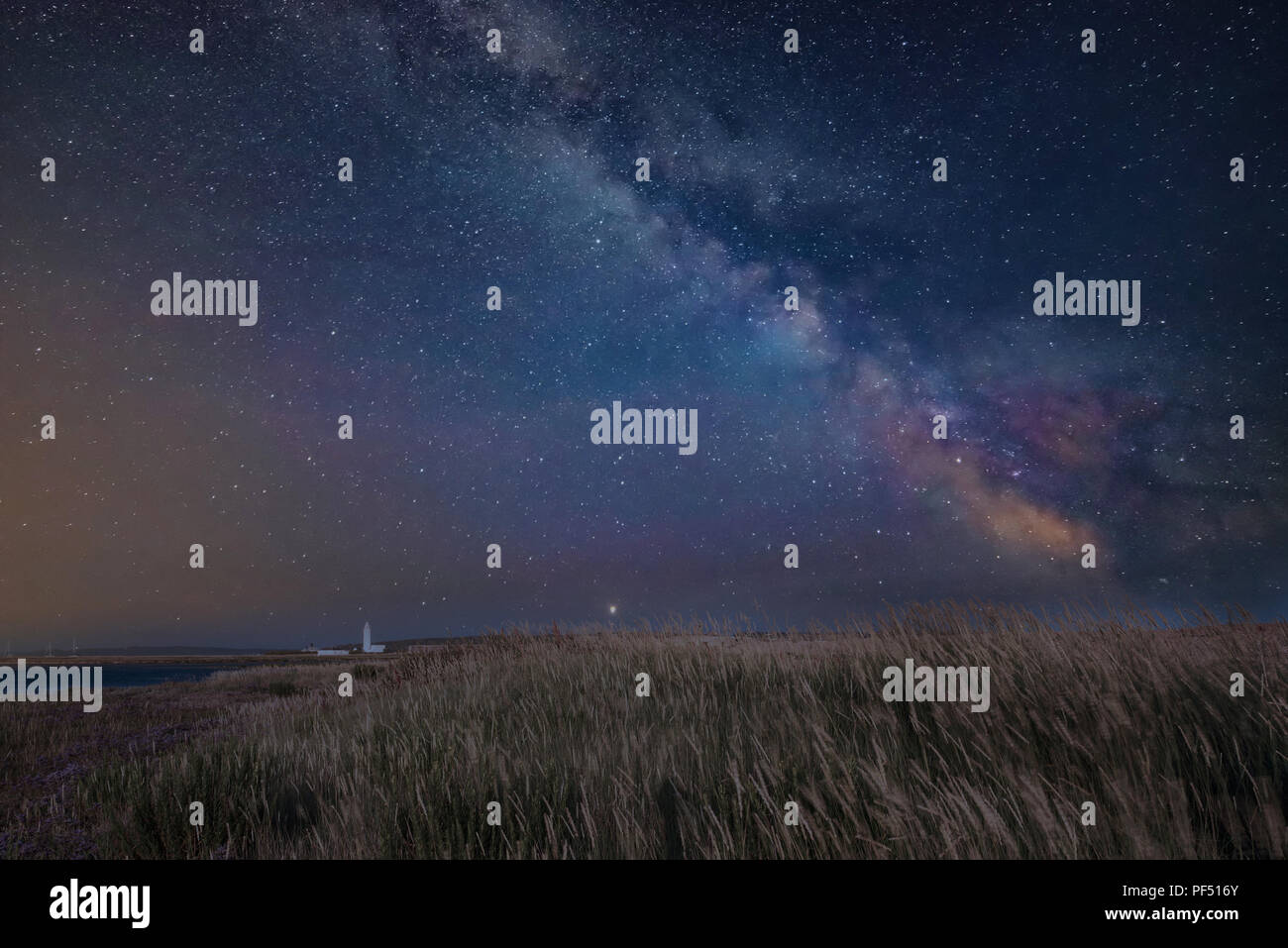 Impresionante vibrante Vía Láctea imagen compuesta a lo largo de paisaje de faro Foto de stock