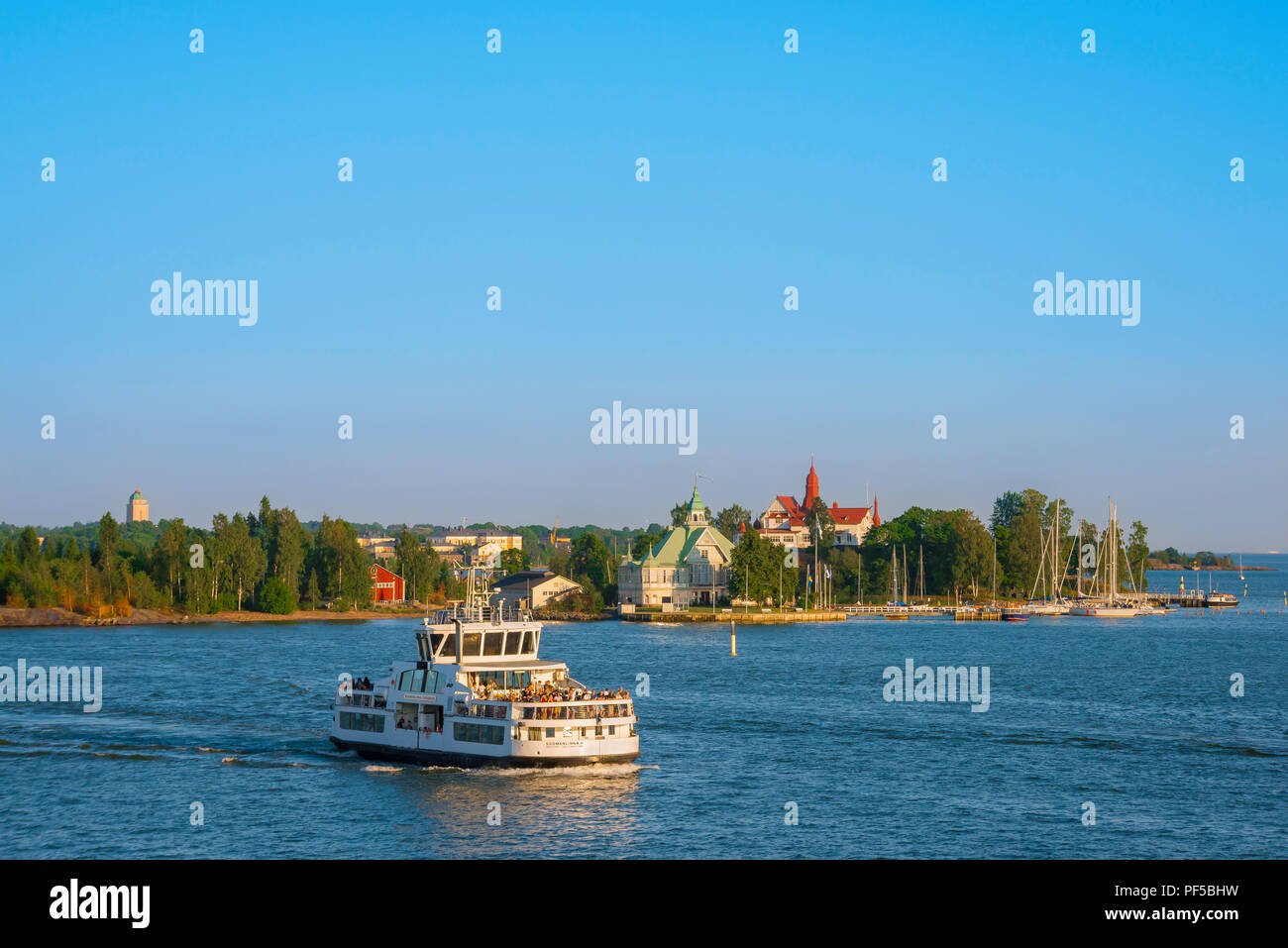 Verano en el puerto de Helsinki, vista al sur por la noche desde el puerto de Helsinki hacia un pequeño ferry que pasa por la isla de Valkosaari, Golfo de Finlandia. Foto de stock