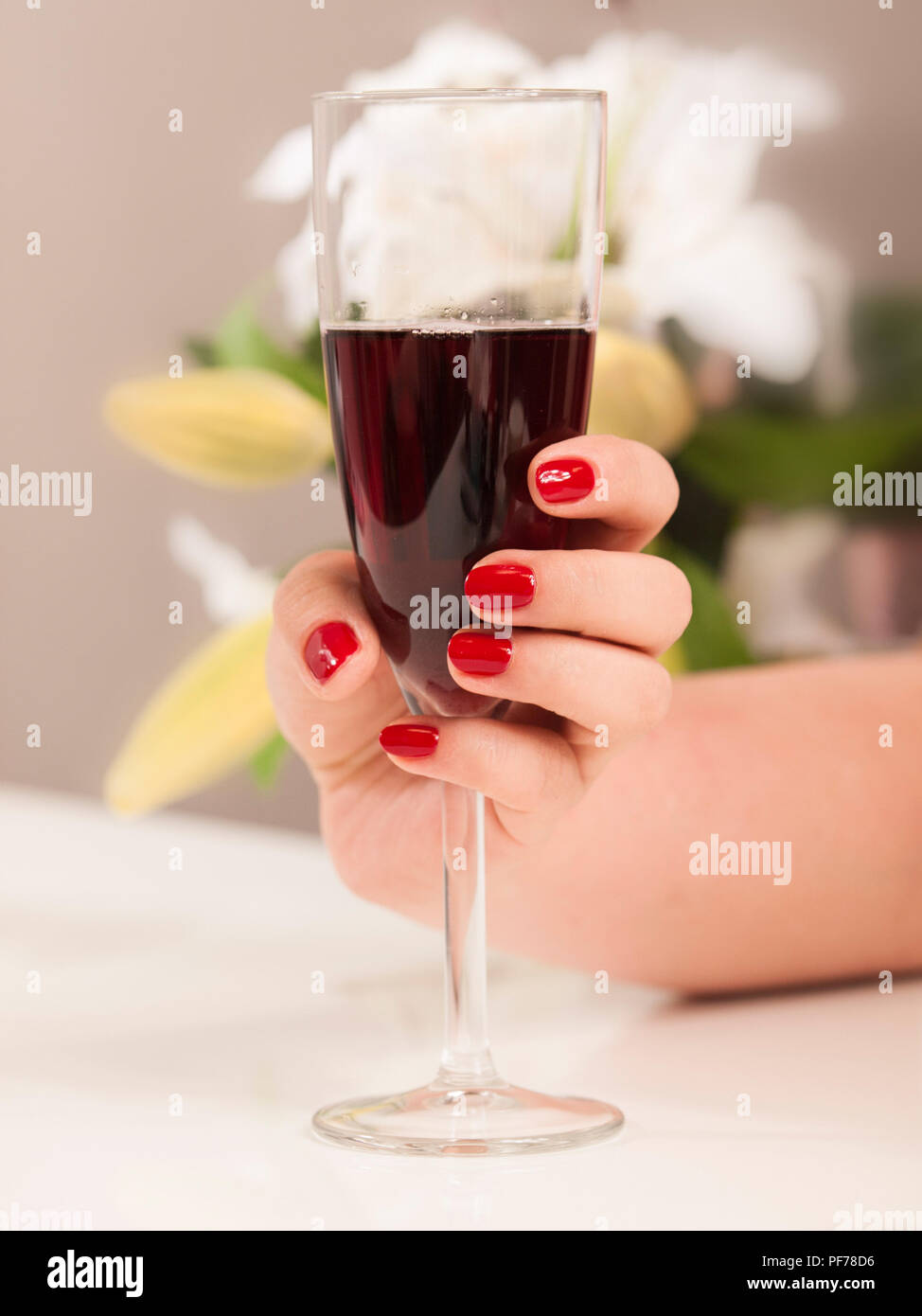 Mujer hermosa mano con pulido nais sosteniendo un vaso de vino tinto Foto de stock