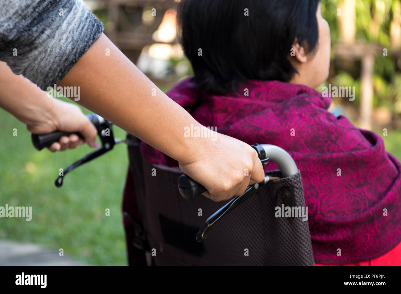 Cuidador empujando altos mujer en silla de ruedas. Foto de stock