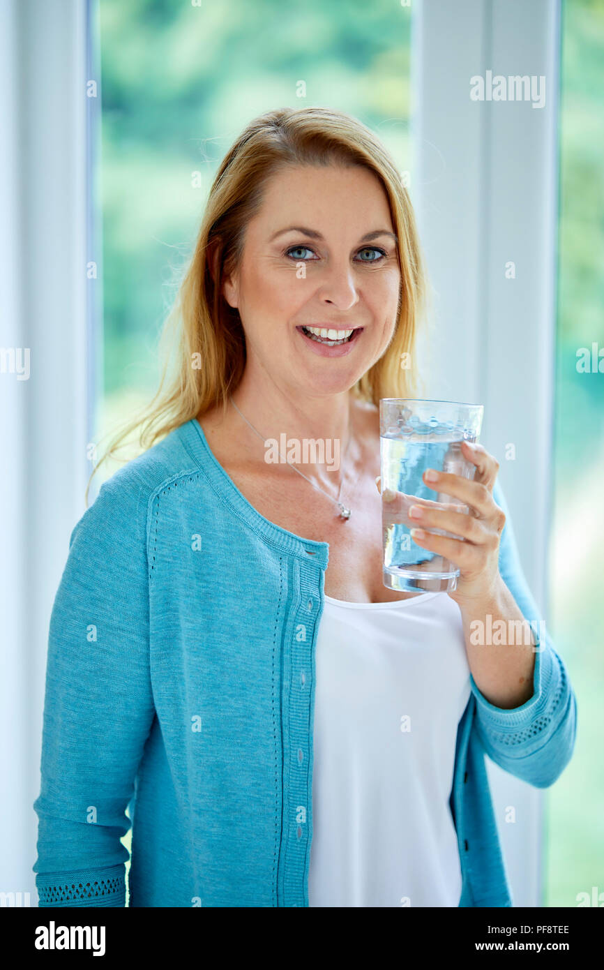 Mujer se situó sostener un vaso de agua. Foto de stock