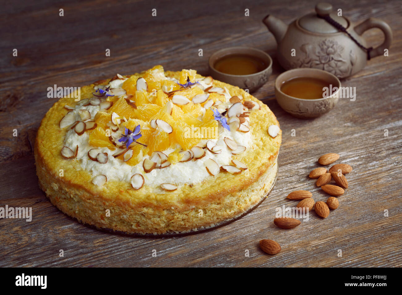 Saludable flourless hecha en casa, sin azúcar, sin lácteos veganas torta de harina de almendras, naranjas y coco, comida artística bodegón con una tetera de barro Foto de stock