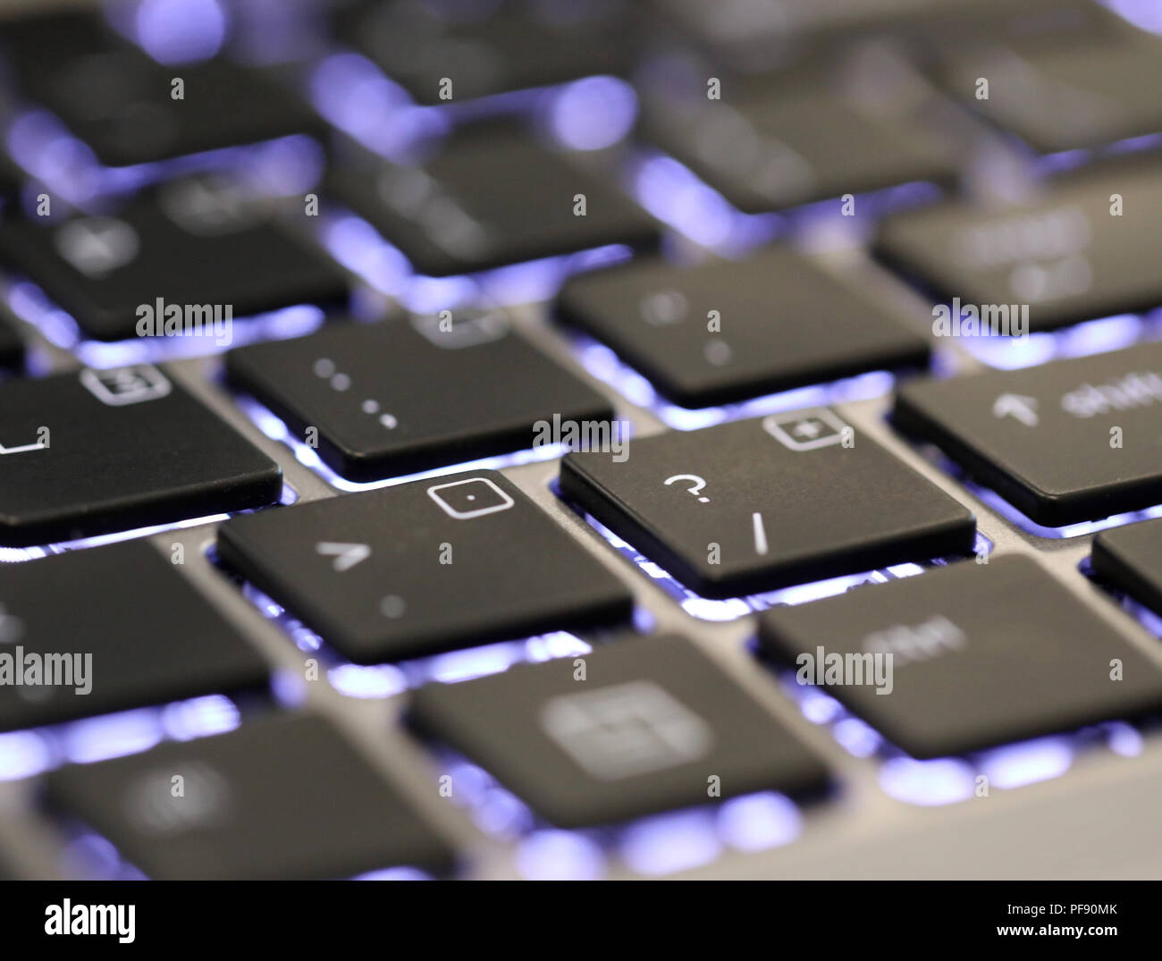 Cerca del símbolo de interrogación un carácter especial en un teclado iluminado en un ordenador portátil o PC. Foto de stock