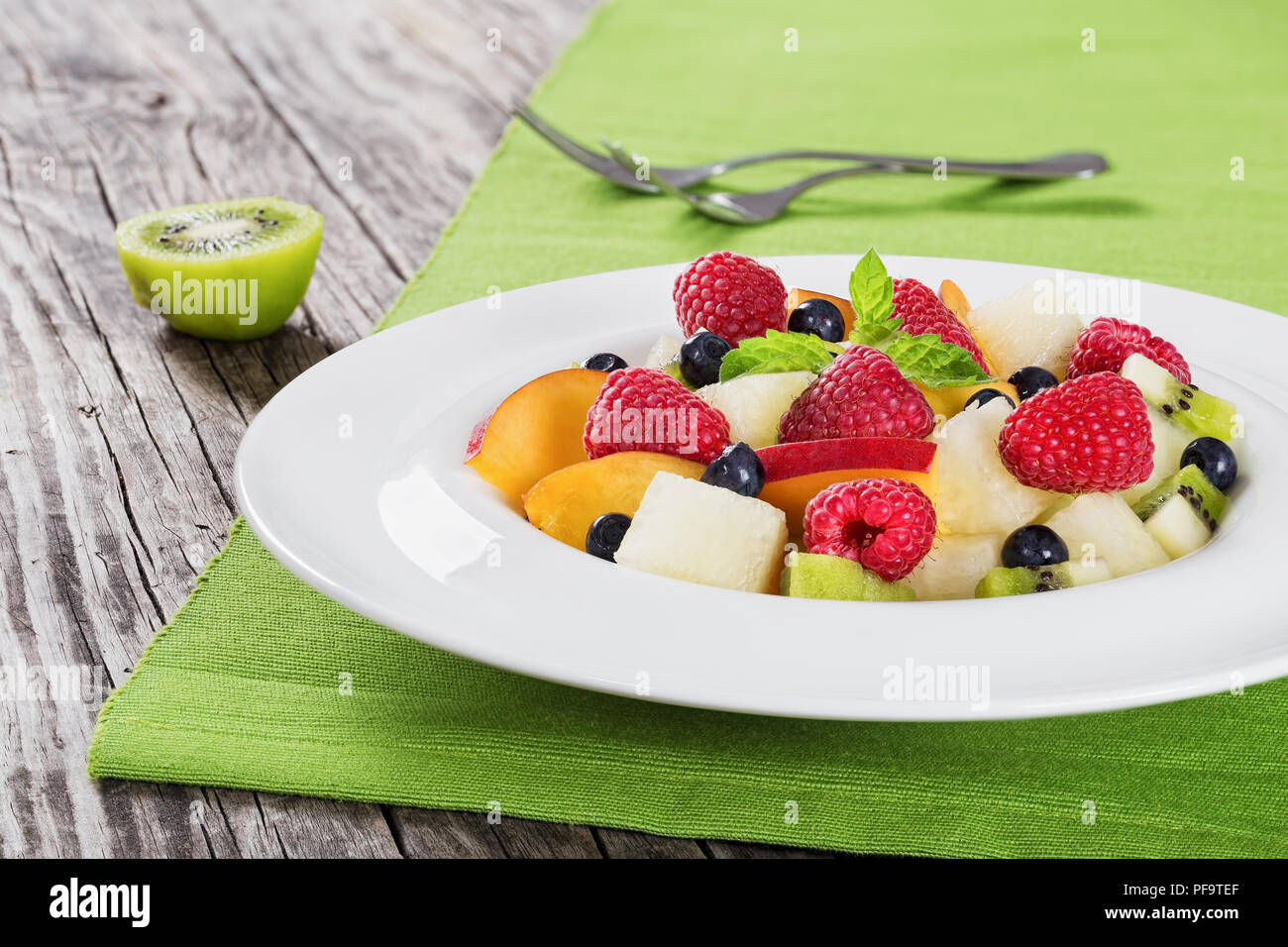 Deliciosas frutas y bayas de ensalada de verano decorado con hojas de menta  en blanco el disco de la llanta sobre tablas de madera, cerrar Fotografía  de stock - Alamy