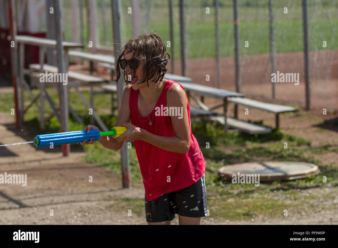 El verano en una guerra de agua. Las hembras jóvenes, en pantalones cortos y rojo corto, disparos de pistola de agua. Riendo y divirtiéndose. Modelo liberado Foto de stock