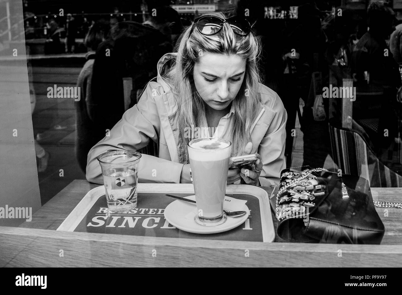 Las mujeres textos en su teléfono mientras que en la cafetería en el centro de la ciudad de Manchester, Reino Unido Foto de stock