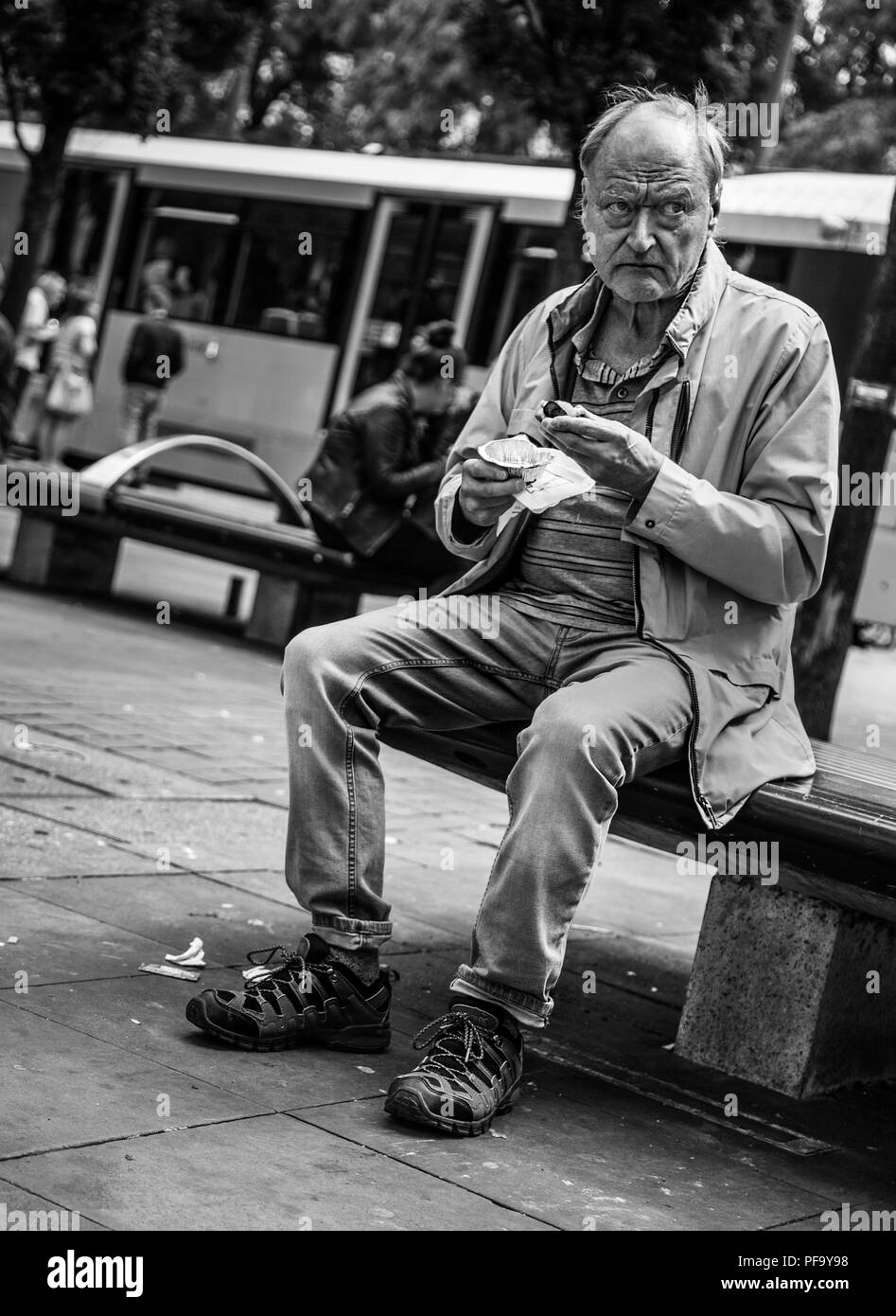 El hombre come pastel de banco en el centro de la ciudad de Manchester, Reino Unido Foto de stock