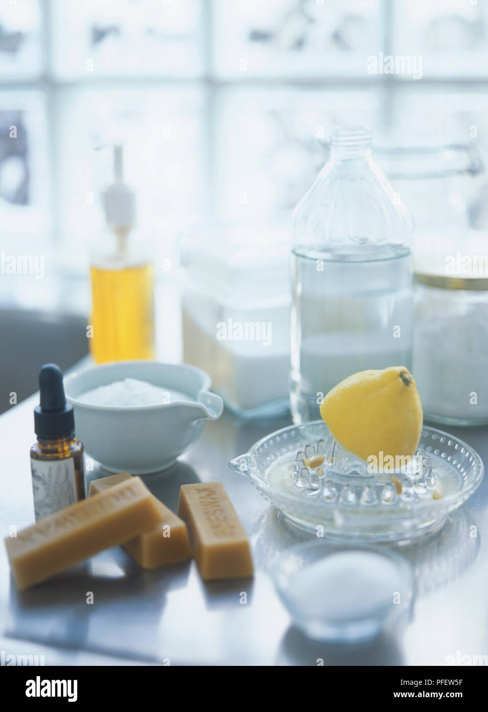 Utensilios de limpieza natural, incluyendo medio limón sobre vidrio  exprimidor, bloques de cera de abeja, vinagre, jabón líquido, bicarbonato  de soda, sal, aceites esenciales Fotografía de stock - Alamy
