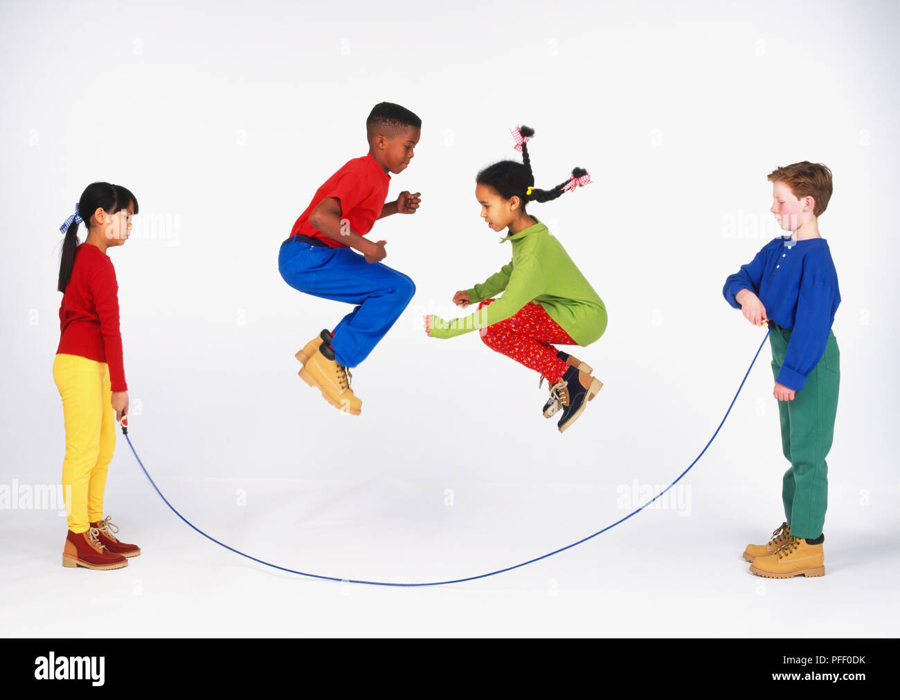 Dos niños sosteniendo una cuerda, y dos niños saltando en el aire  Fotografía de stock - Alamy