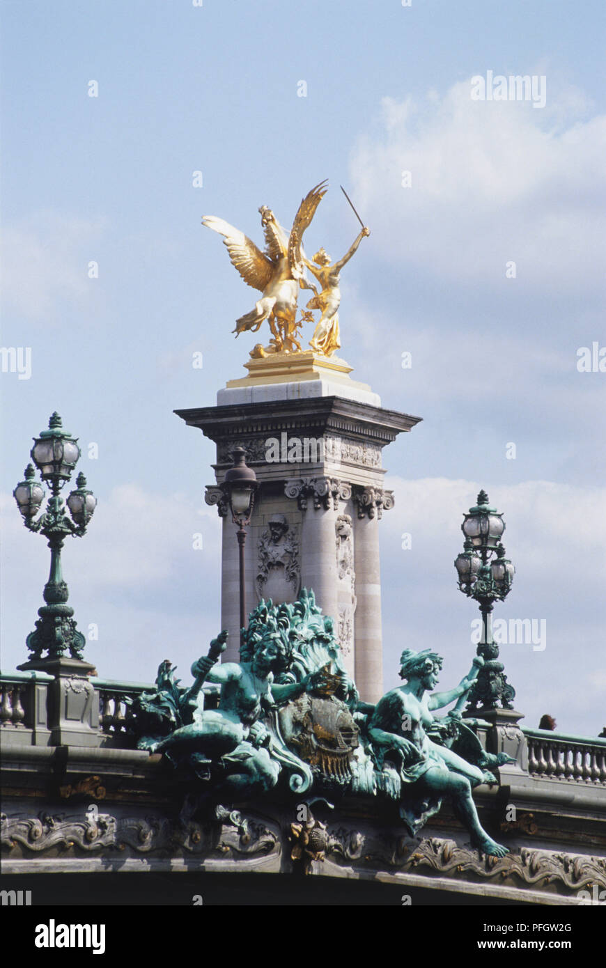 Francia, Paris, Pont Alexander III con una columna de piedra decorativa rodamiento grabados y un querubín soplando un cuerno dorado, puente con bronce y las estatuas doradas. Foto de stock