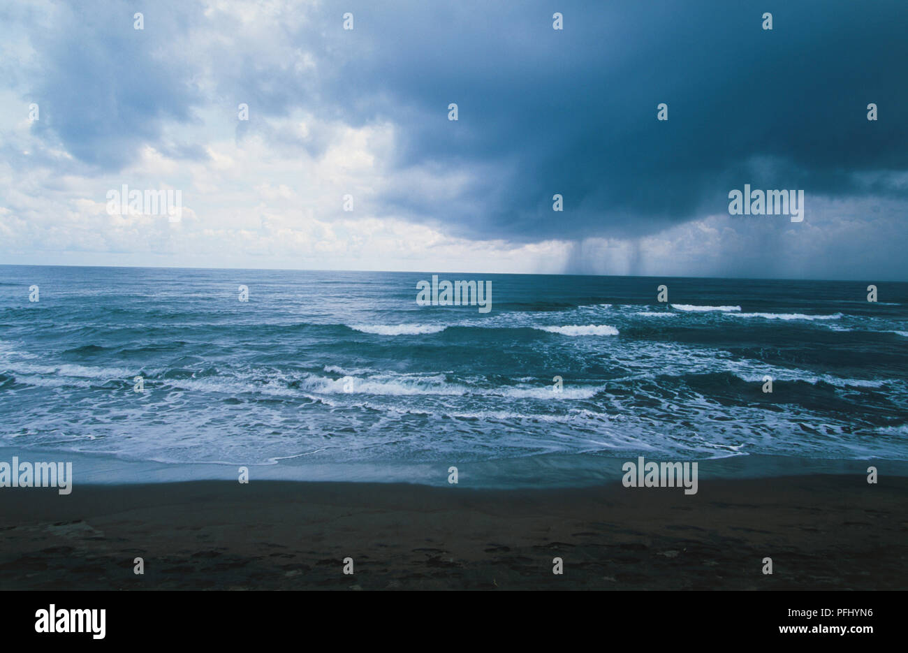 En Centroamérica, Costa Rica, El Caribe, el Parque Nacional Tortuguero, olas rompiendo en la playa desierta en el mar frente a la aldea durante condiciones climáticas tormentosas y oscuras nubes de lluvia encima en día nublado en el parque nacional Foto de stock