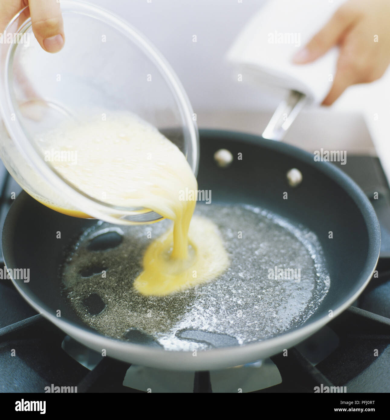 Batido huevo crudo que se vierte sobre las calientes grasa en sartén, vista  lateral Fotografía de stock - Alamy